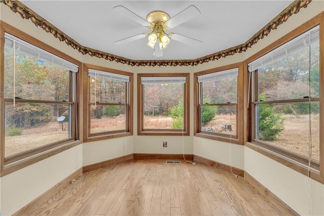 unfurnished sunroom featuring ceiling fan and plenty of natural light