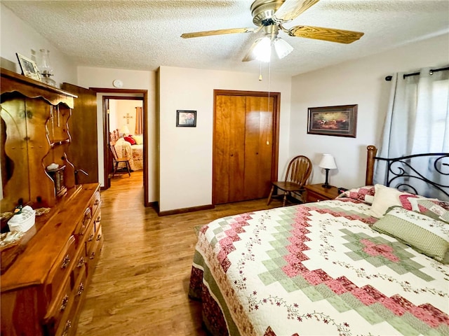 bedroom with light hardwood / wood-style flooring, a textured ceiling, a closet, and ceiling fan