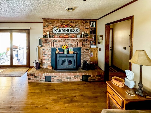 living room with crown molding, wood-type flooring, a textured ceiling, and a wood stove