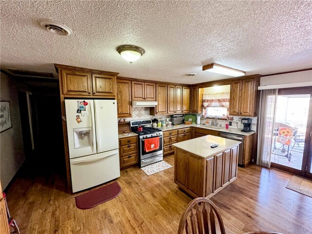 kitchen featuring a kitchen island, stainless steel appliances, sink, light wood-type flooring, and a textured ceiling