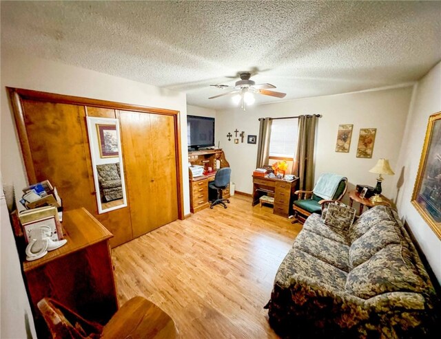 living room featuring ceiling fan, wood-type flooring, and a textured ceiling