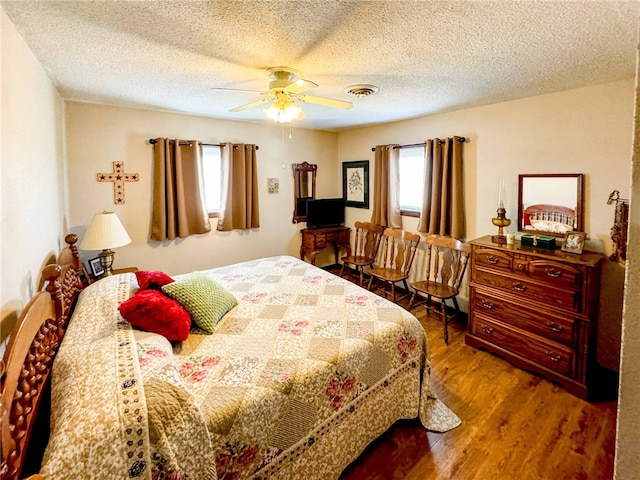 bedroom with hardwood / wood-style floors, a textured ceiling, and ceiling fan