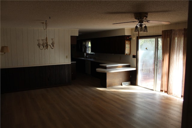 kitchen with wood walls, a textured ceiling, hardwood / wood-style flooring, and ceiling fan with notable chandelier