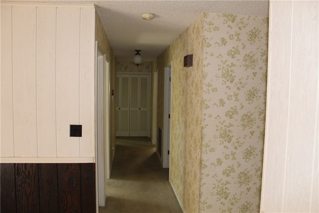 hallway featuring carpet flooring and a textured ceiling