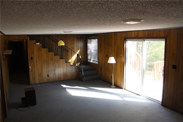 unfurnished living room featuring wooden walls and a textured ceiling