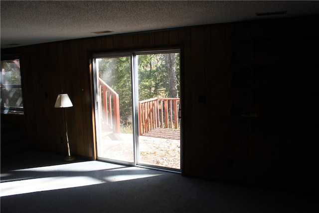 carpeted empty room with a textured ceiling and wooden walls