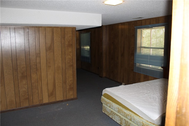 carpeted bedroom with wood walls and a textured ceiling