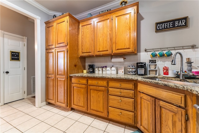 kitchen featuring light stone counters, decorative backsplash, sink, light tile patterned flooring, and crown molding