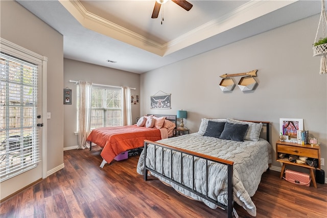 bedroom featuring dark wood-type flooring, ceiling fan, a raised ceiling, and ornamental molding