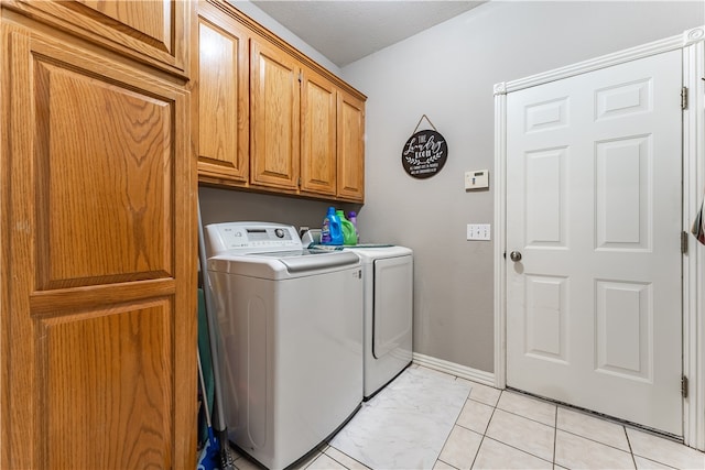 laundry room featuring cabinets, washing machine and dryer, a textured ceiling, and light tile patterned floors