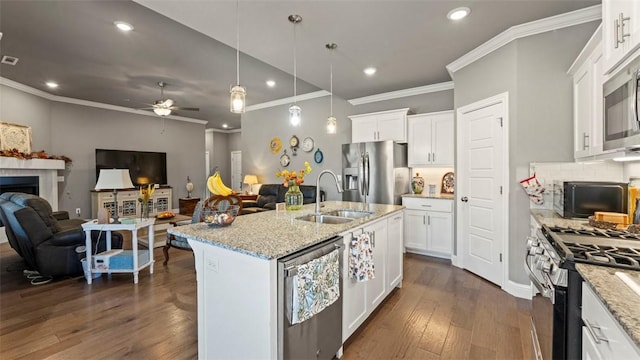 kitchen with a fireplace, stainless steel appliances, open floor plan, white cabinetry, and a sink