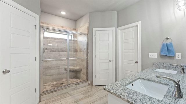 full bathroom with double vanity, a stall shower, a sink, and wood tiled floor