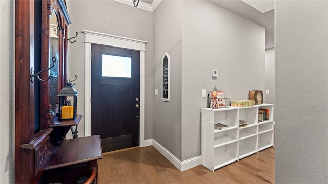 entrance foyer with arched walkways, crown molding, baseboards, and wood finished floors