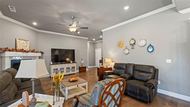 living area with baseboards, visible vents, ceiling fan, wood finished floors, and a fireplace