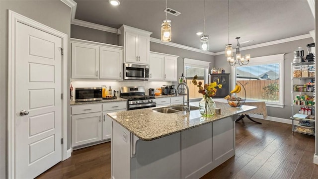 kitchen featuring stainless steel appliances, a sink, visible vents, white cabinets, and decorative light fixtures