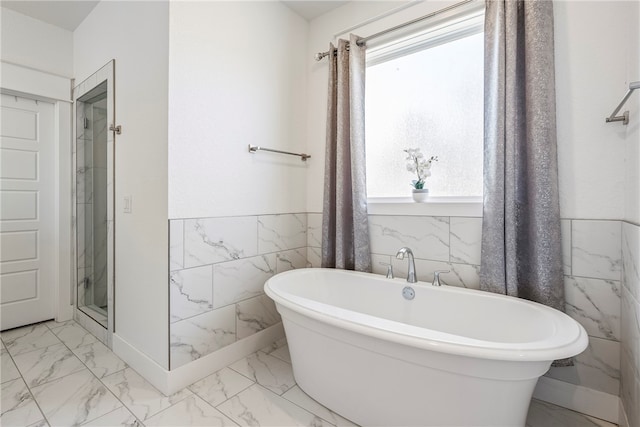 bathroom with shower with separate bathtub and tile walls