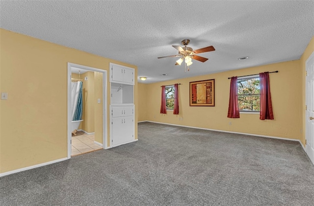 spare room featuring a textured ceiling, light colored carpet, and ceiling fan