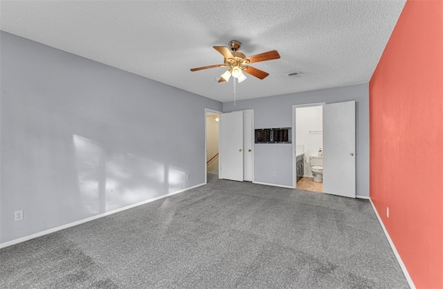 unfurnished bedroom with carpet floors, ensuite bathroom, a textured ceiling, and ceiling fan