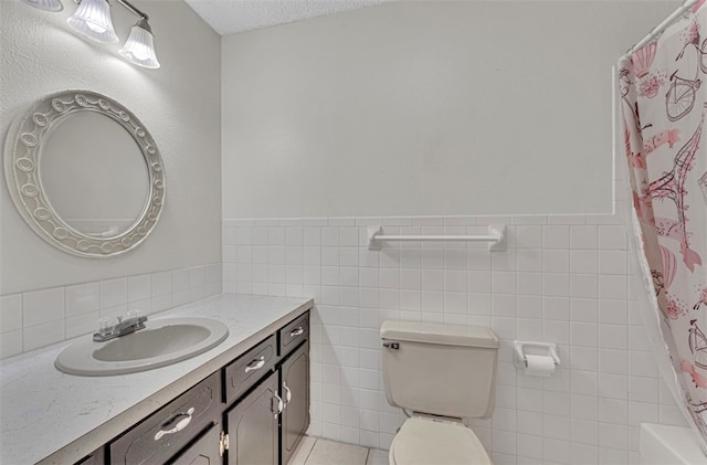 bathroom featuring toilet, a shower with shower curtain, tile walls, vanity, and a textured ceiling