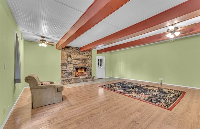 living room with light hardwood / wood-style flooring, beamed ceiling, a fireplace, and ceiling fan