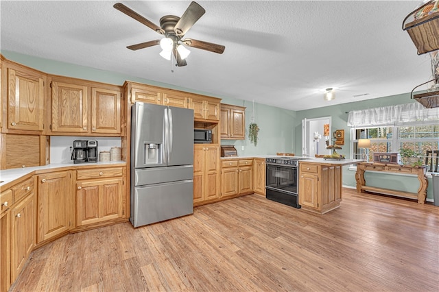 kitchen featuring kitchen peninsula, appliances with stainless steel finishes, a textured ceiling, and light hardwood / wood-style flooring