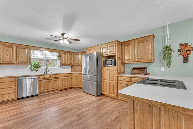 kitchen with stainless steel appliances, light hardwood / wood-style floors, sink, ceiling fan, and a textured ceiling