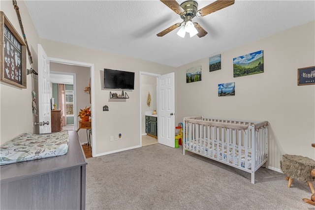 bedroom featuring carpet, a textured ceiling, ceiling fan, and a crib