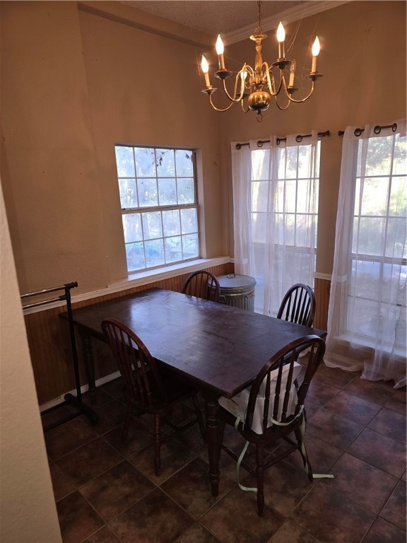 dining room with a notable chandelier, dark tile patterned floors, crown molding, and a wealth of natural light