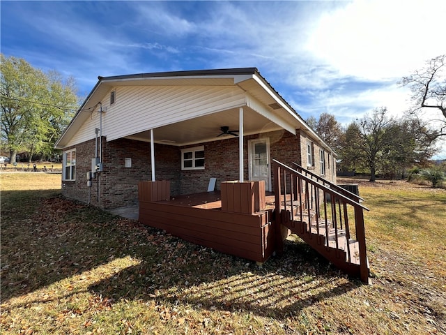 view of side of property with ceiling fan and a lawn