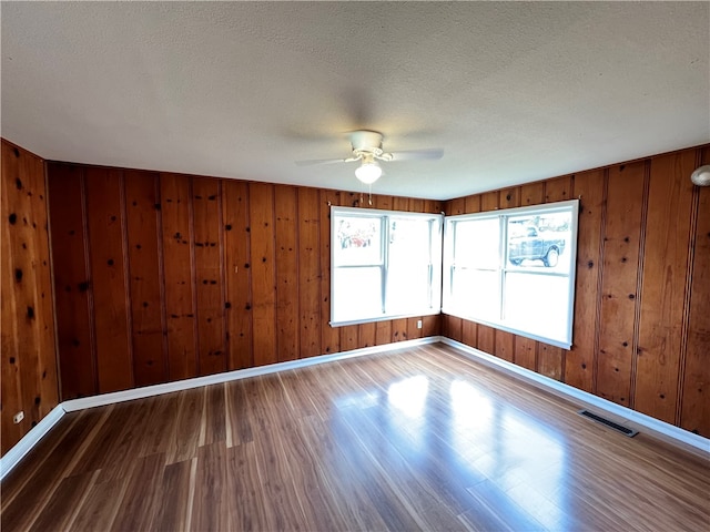 empty room with wood walls, hardwood / wood-style floors, and a textured ceiling