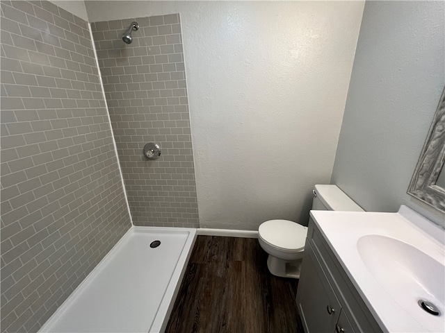 bathroom with vanity, toilet, wood-type flooring, and tiled shower