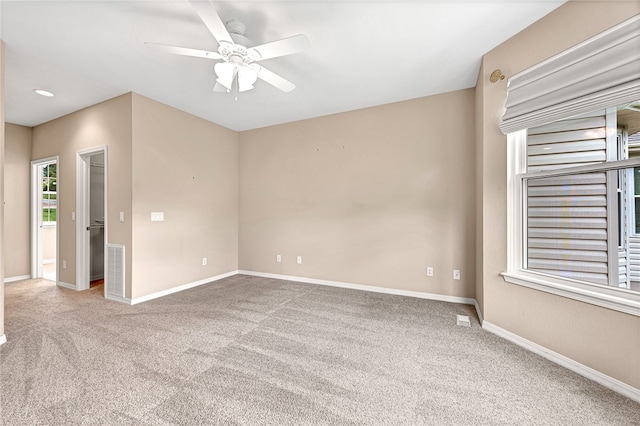 spare room featuring carpet, visible vents, ceiling fan, and baseboards