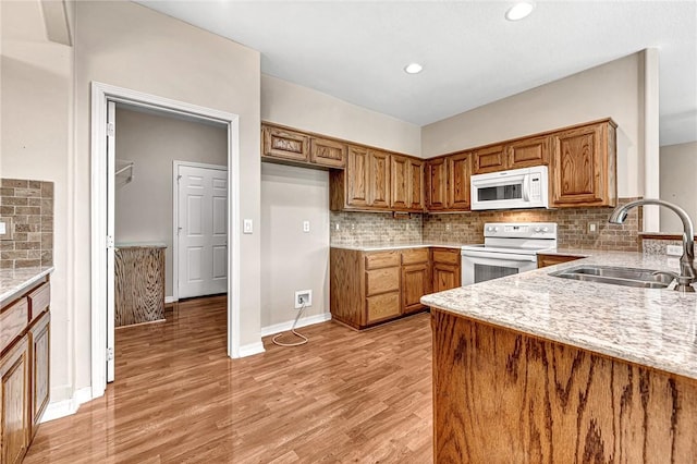 kitchen with white appliances, light wood-type flooring, light stone counters, decorative backsplash, and sink