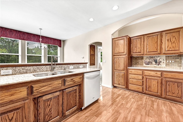 kitchen featuring a sink, brown cabinets, decorative backsplash, dishwasher, and light wood finished floors