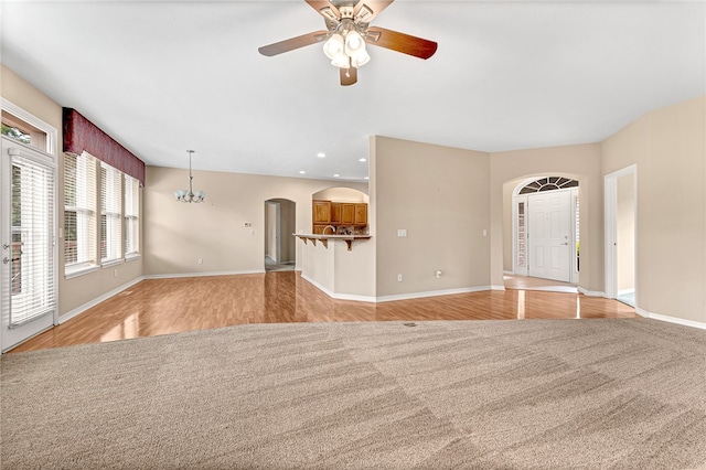 unfurnished living room featuring light wood-style floors, baseboards, arched walkways, and recessed lighting