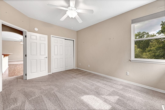 unfurnished bedroom with a closet, carpet, a ceiling fan, and baseboards