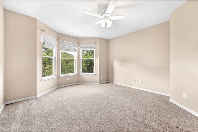 carpeted empty room featuring ceiling fan, visible vents, and baseboards