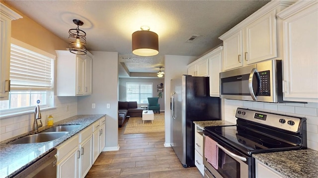 kitchen featuring light hardwood / wood-style floors, pendant lighting, sink, stainless steel appliances, and white cabinets