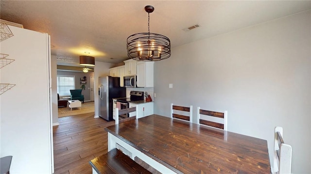 dining area with dark wood-type flooring and a notable chandelier