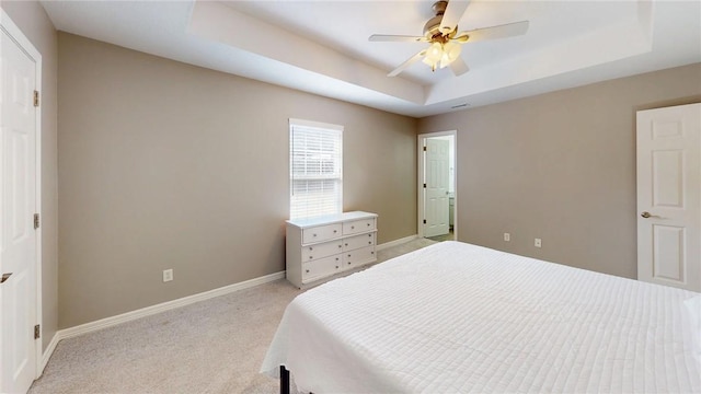 carpeted bedroom featuring ceiling fan and a tray ceiling