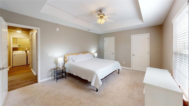 carpeted bedroom featuring a raised ceiling, ceiling fan, and washing machine and clothes dryer