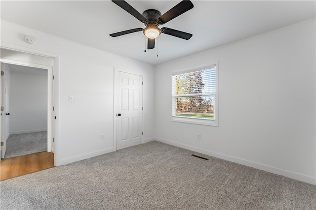 unfurnished bedroom with ceiling fan, a closet, carpet floors, and ornamental molding