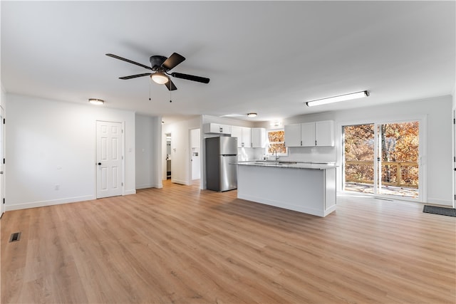 unfurnished living room with light hardwood / wood-style floors, ceiling fan, and sink