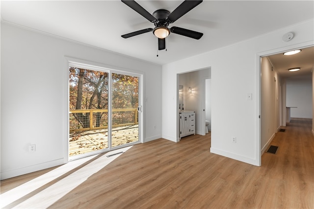 interior space with light wood-type flooring, access to outside, ceiling fan, and connected bathroom