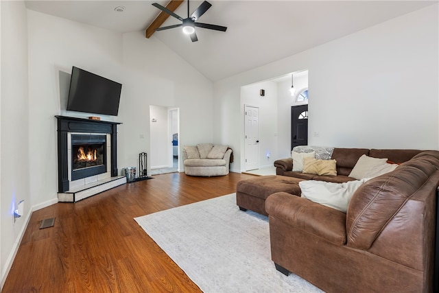 living room featuring hardwood / wood-style flooring, beamed ceiling, a tiled fireplace, ceiling fan, and high vaulted ceiling