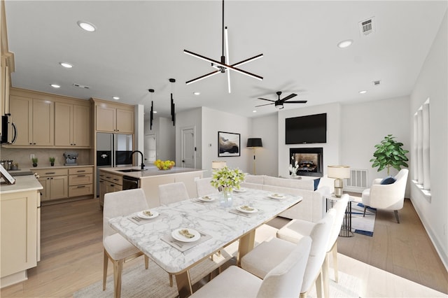 dining area featuring light wood-style floors, recessed lighting, visible vents, and a multi sided fireplace