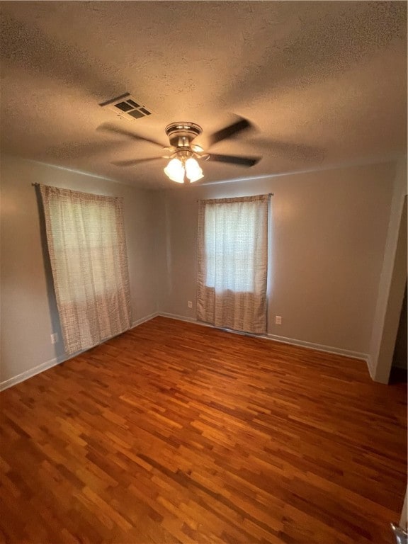 spare room featuring wood-type flooring, ceiling fan, and a textured ceiling