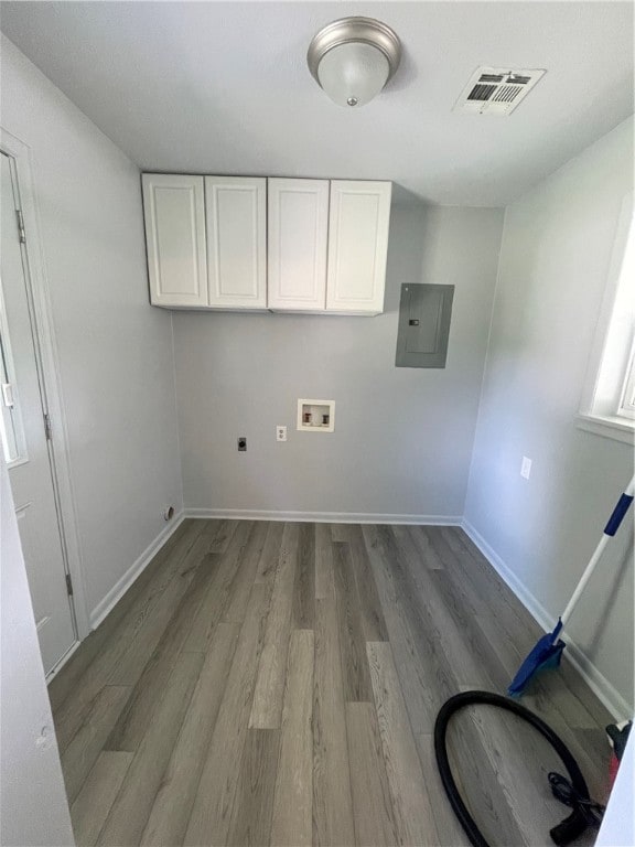 clothes washing area featuring cabinets, hardwood / wood-style flooring, hookup for an electric dryer, electric panel, and hookup for a washing machine