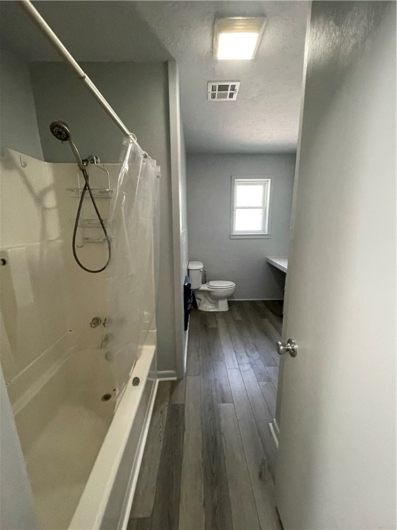 bathroom with hardwood / wood-style flooring, shower / bath combo with shower curtain, and toilet