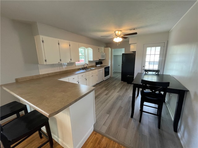 kitchen with white appliances, white cabinetry, sink, and a healthy amount of sunlight